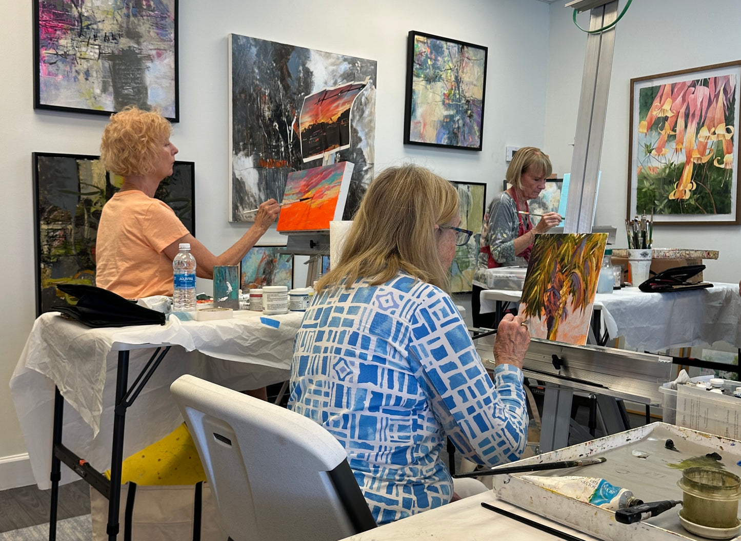 Artists working on paintings in a studio with colorful artwork on the walls.